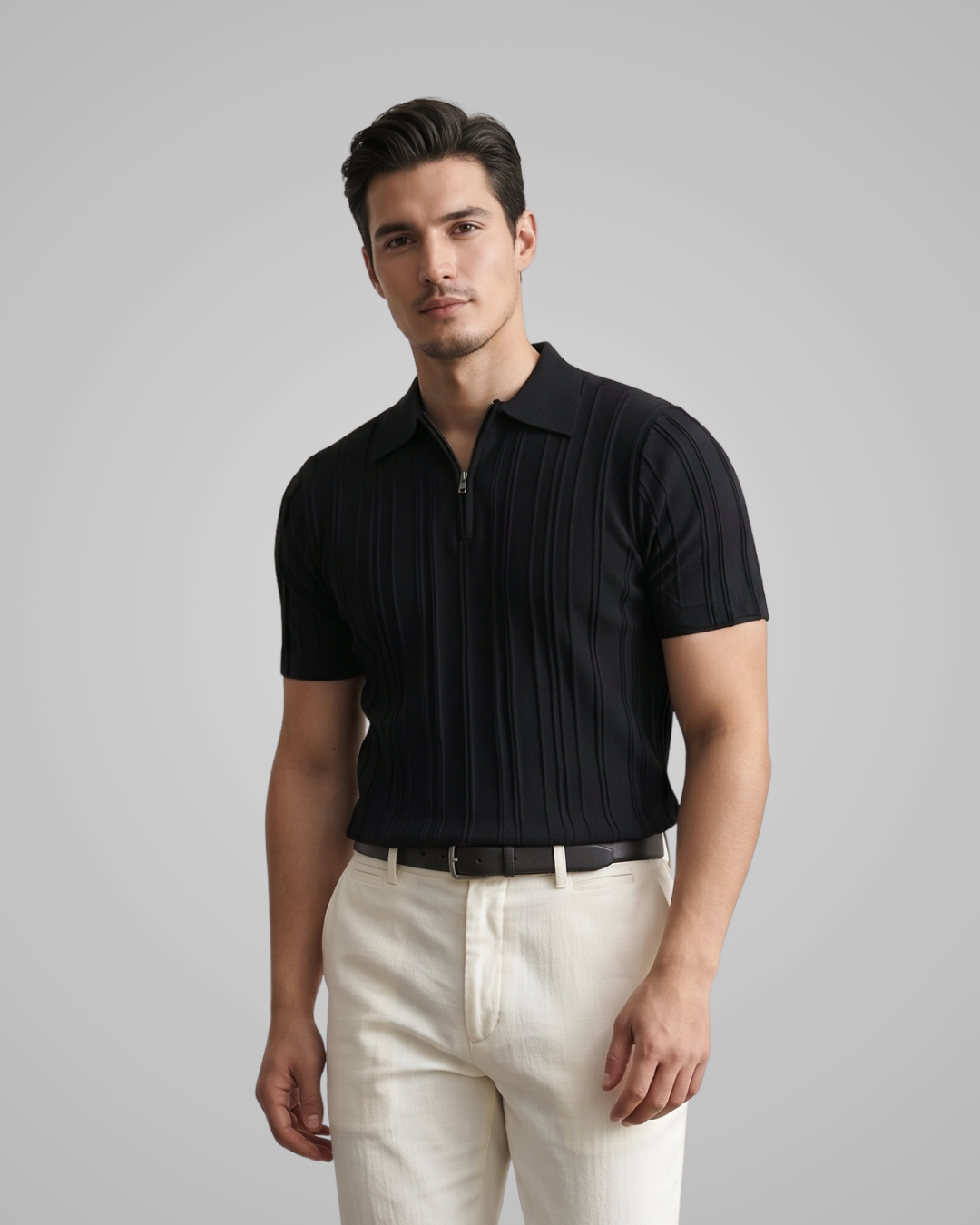 Man wearing a black ribbed polo shirt and white pants on a gray background