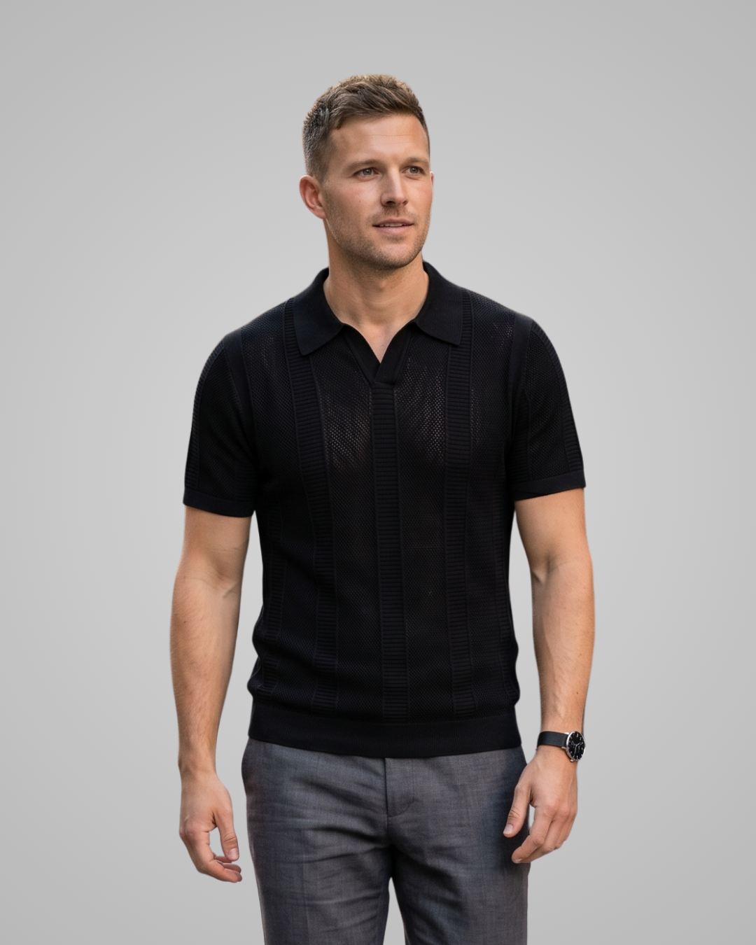 Man wearing a black polo shirt and gray pants against a gray background