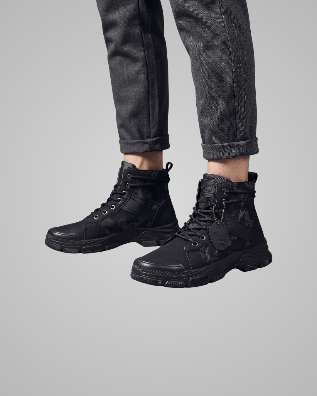 Black boots worn with black pants on a gray background