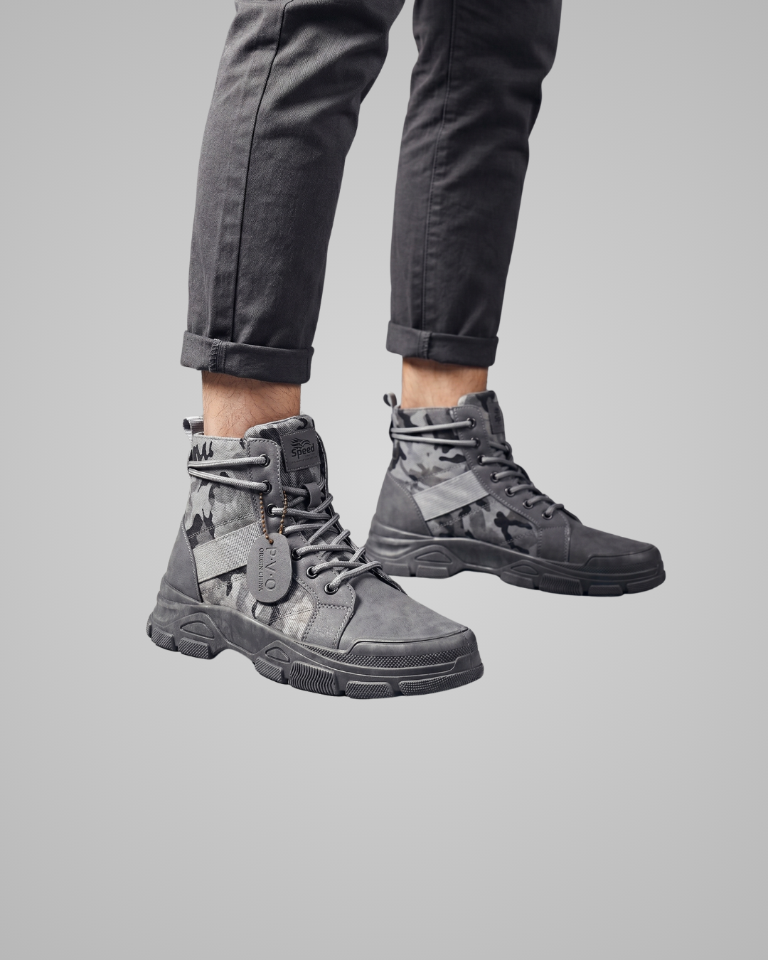 Gray tactical boots worn with rolled-up black pants on a gray background
