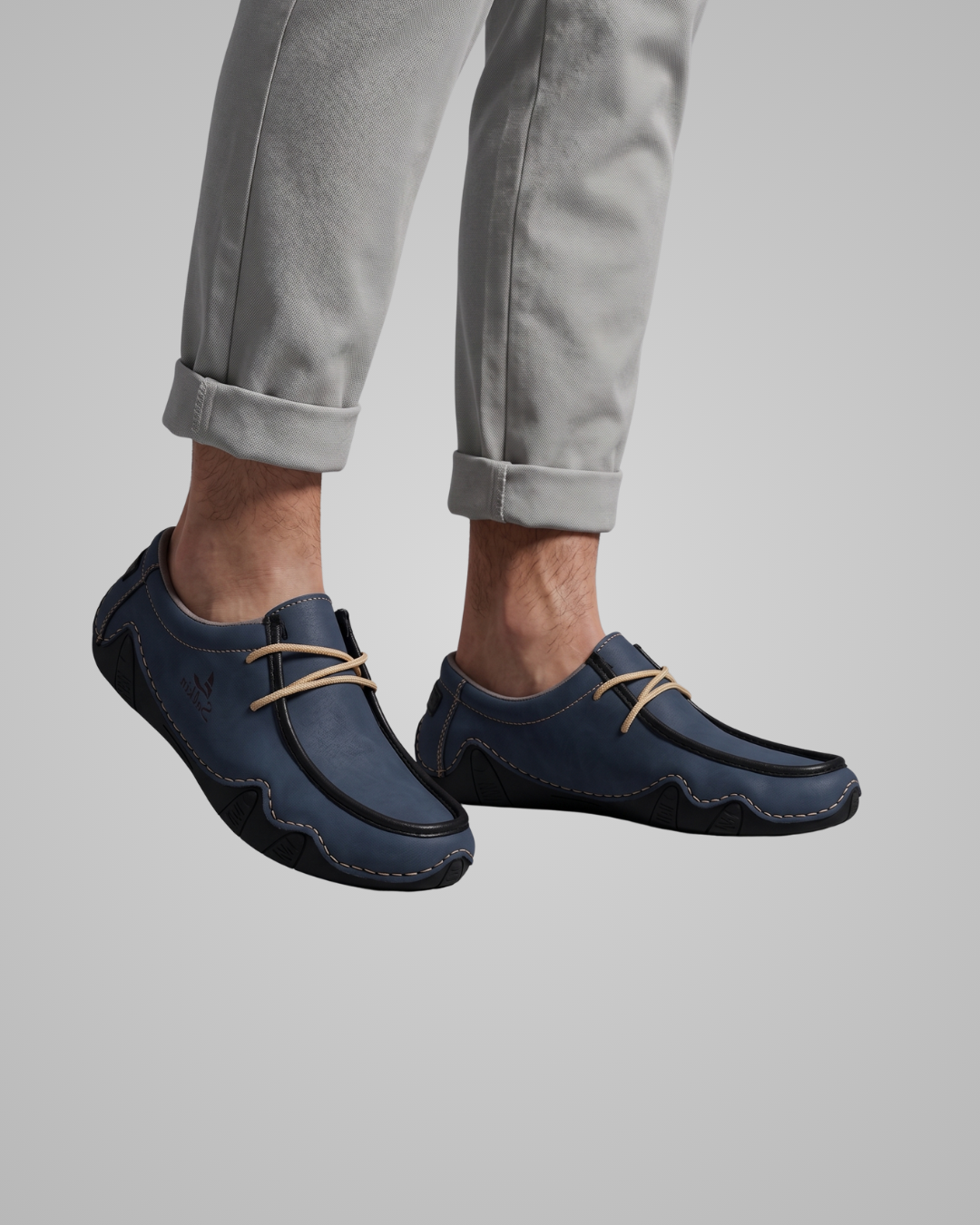 Navy blue loafers worn with light gray pants on a plain background