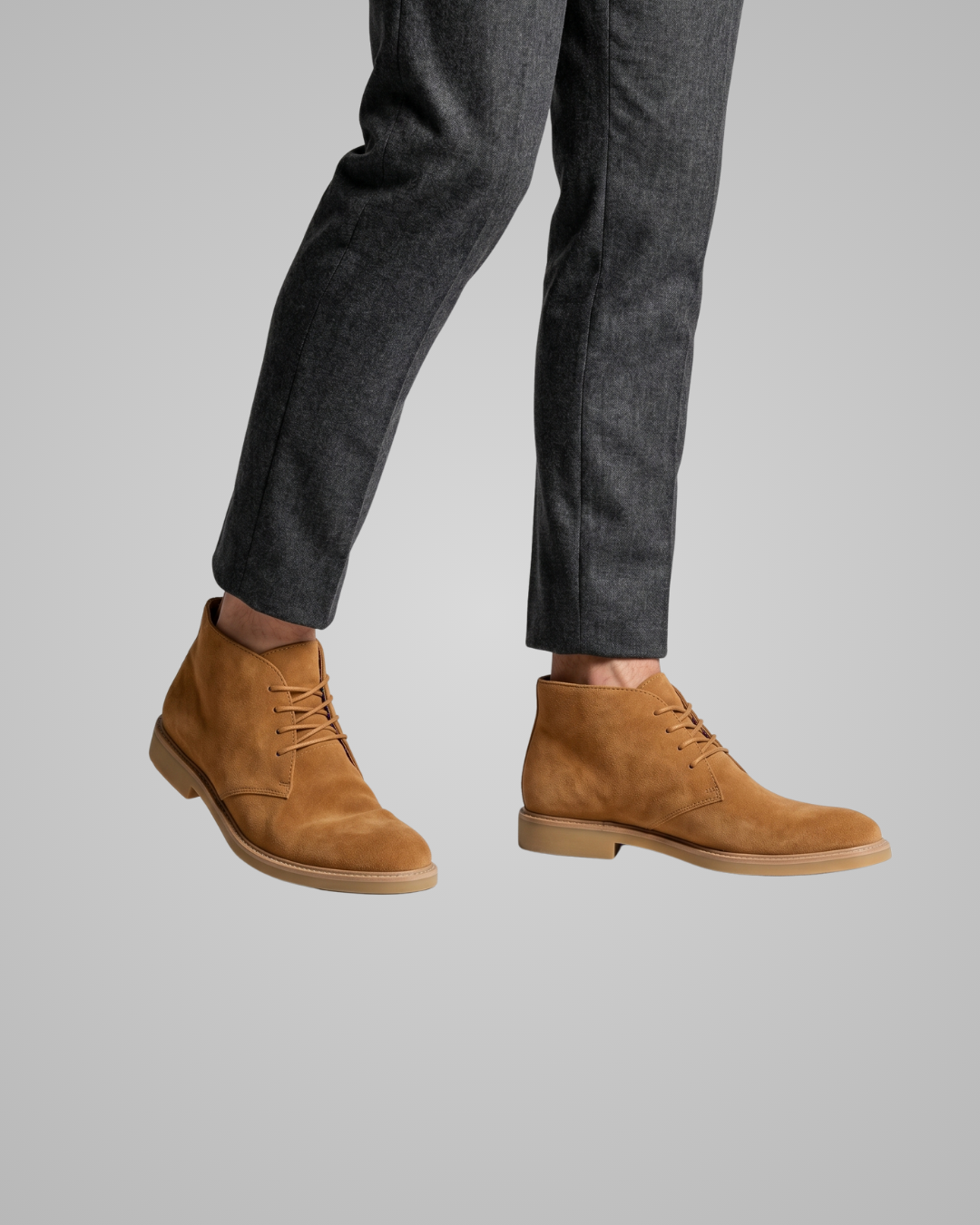 Brown dress shoes worn with gray pants on a light gray background
