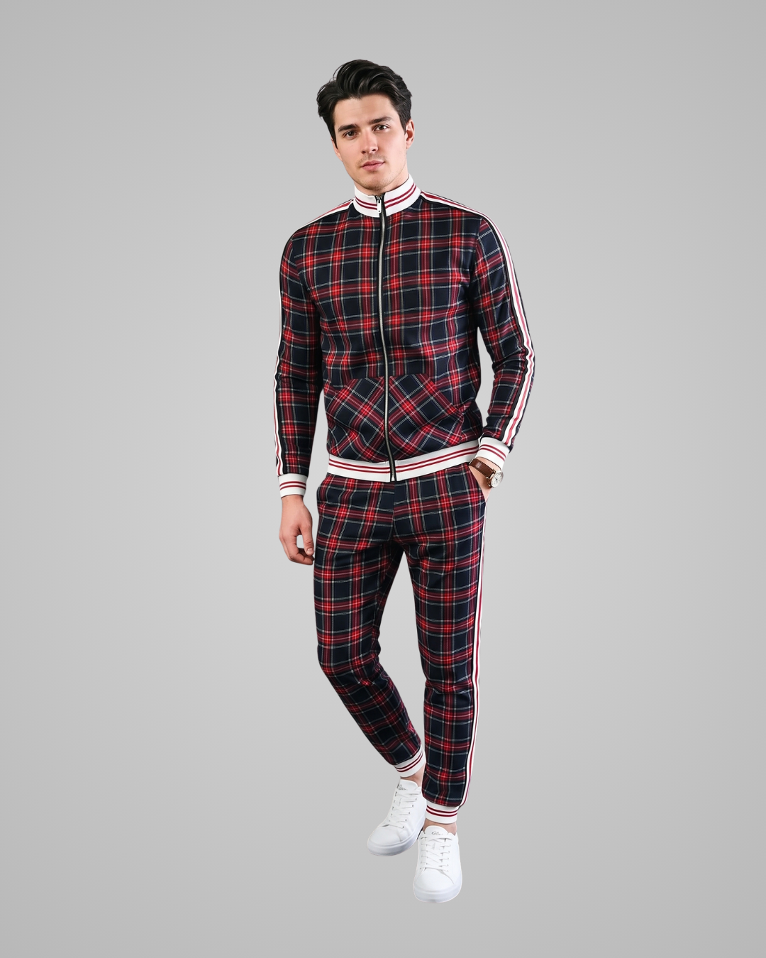 Man wearing a red and black plaid tracksuit with white stripes on a gray background