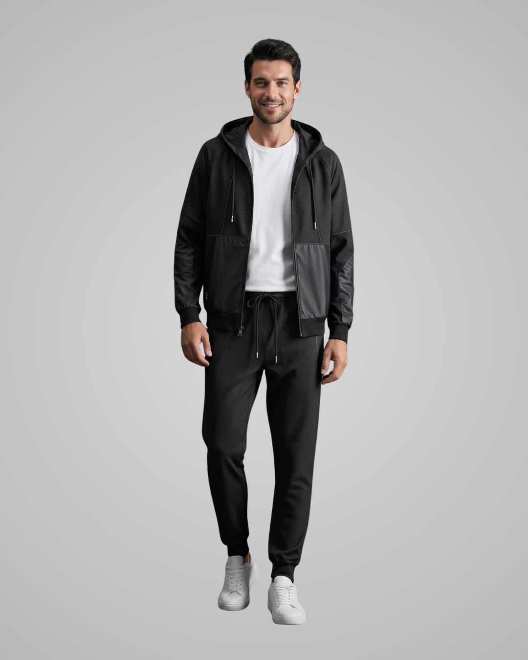Man wearing a black jacket and pants with a white shirt on a gray background