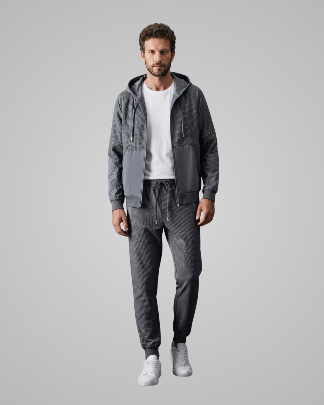 Man wearing a blue tracksuit with a white shirt underneath on a light gray background
