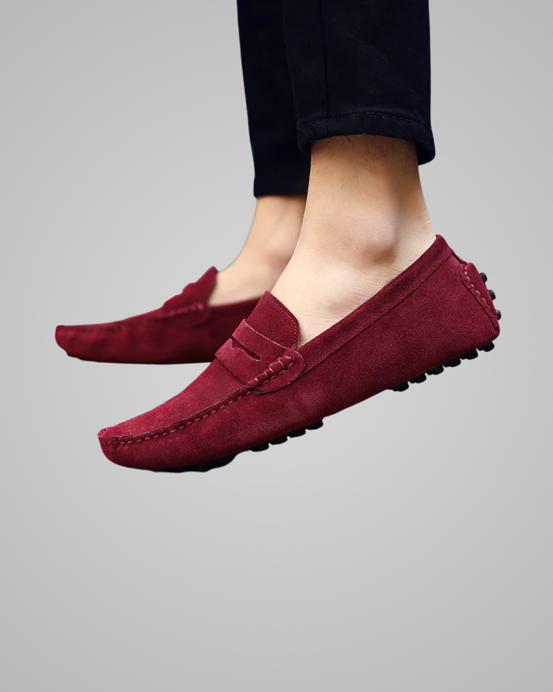 Maroon loafers worn with black pants on a gray background