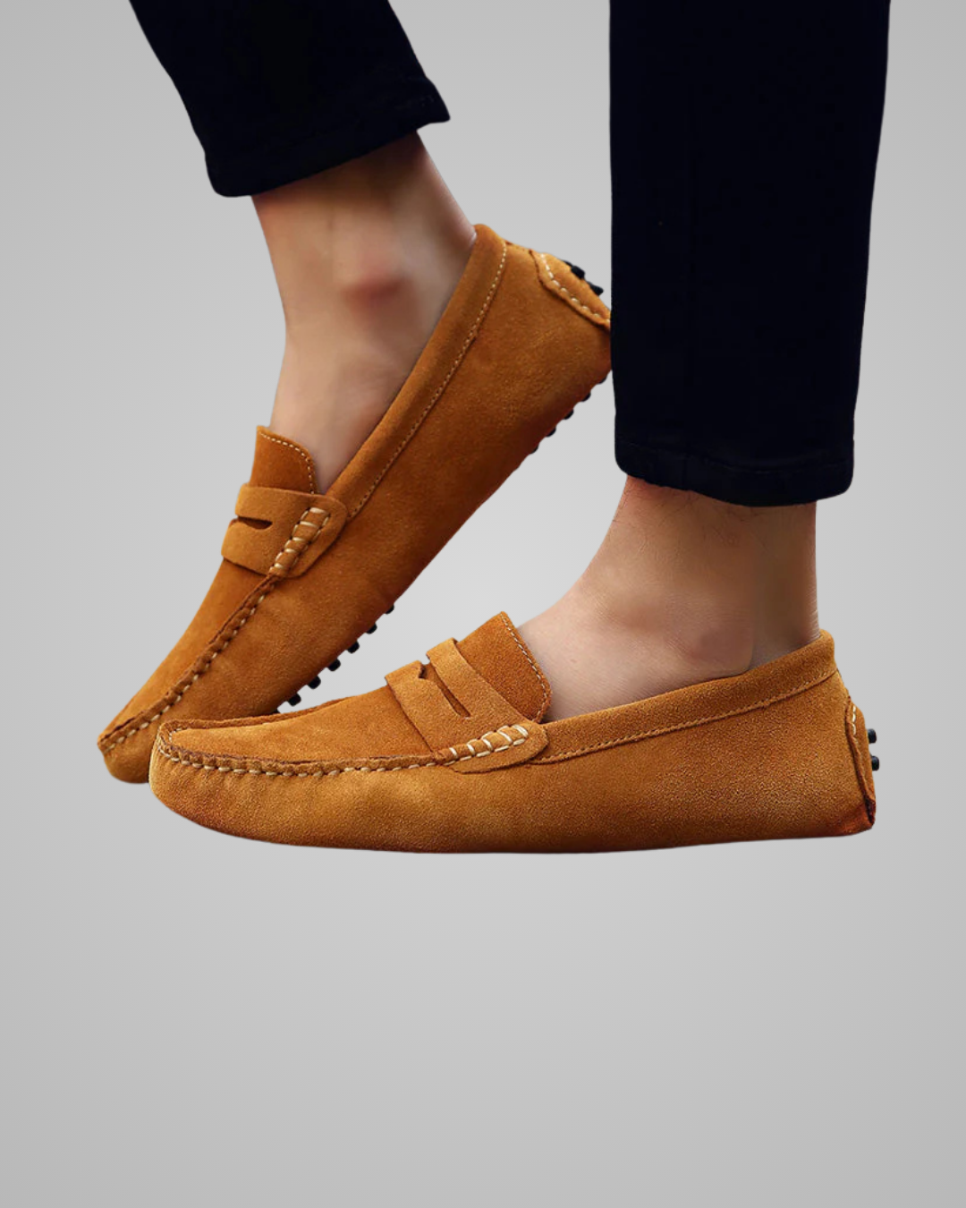 Brown loafers worn with black pants on a gray background