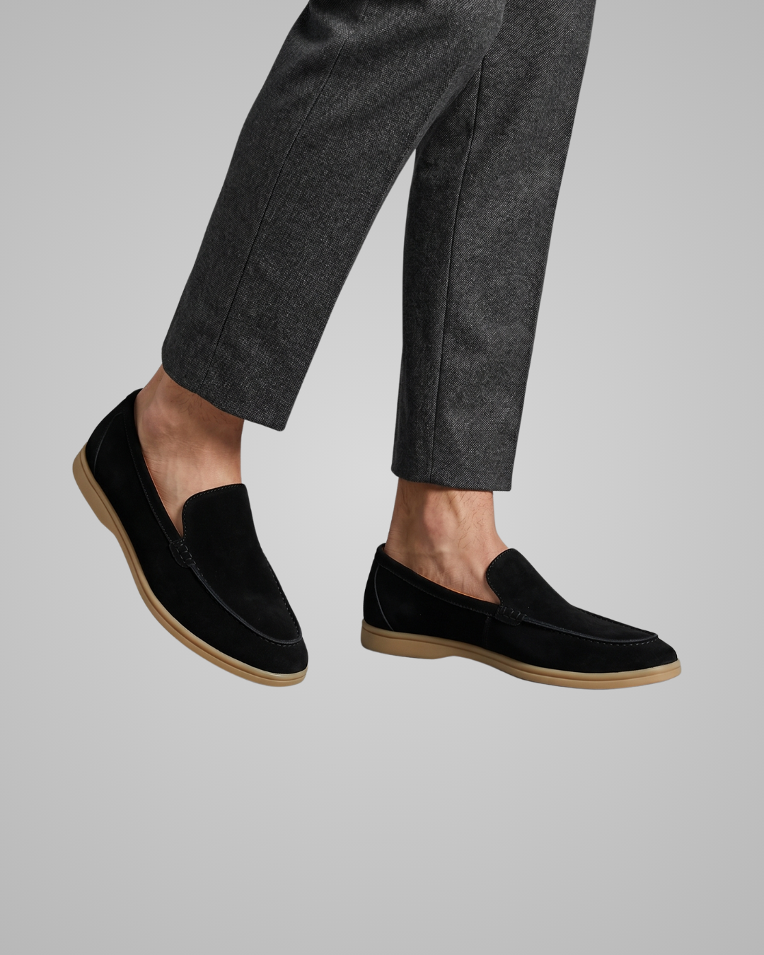 Black loafers worn with gray pants on a light gray background