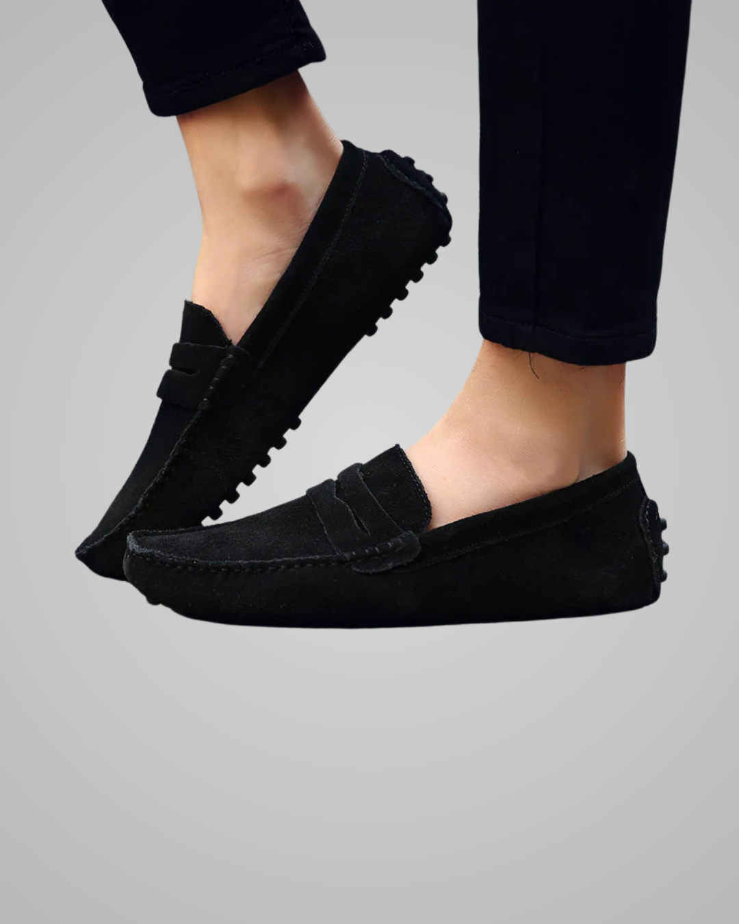 Black loafers worn by a person on a gray background