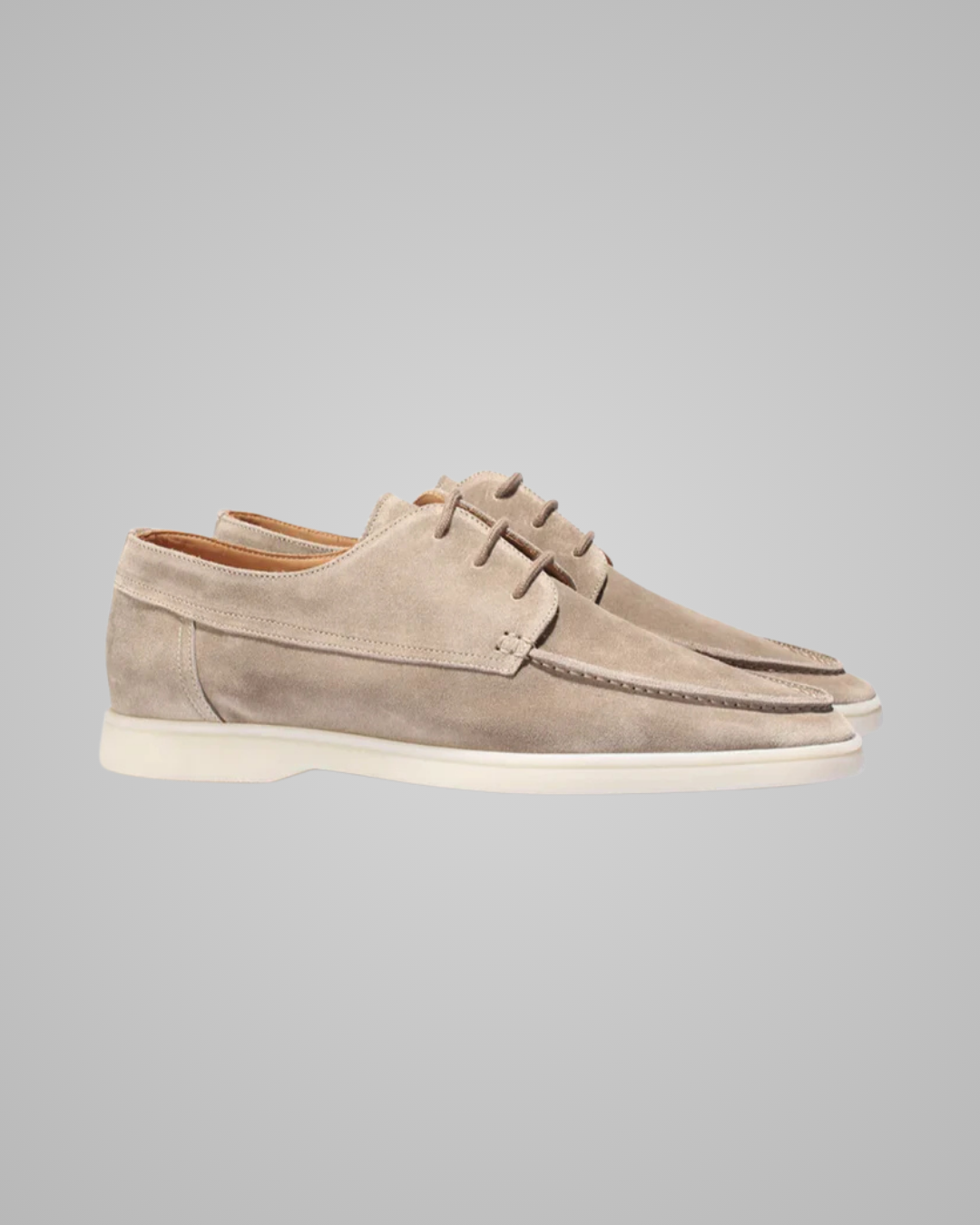 Pair of beige suede shoes on a gray background
