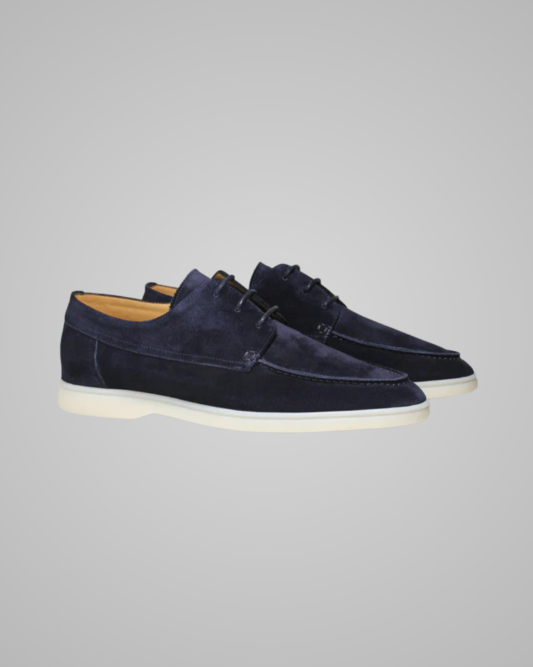 Pair of navy blue suede shoes on a gray background