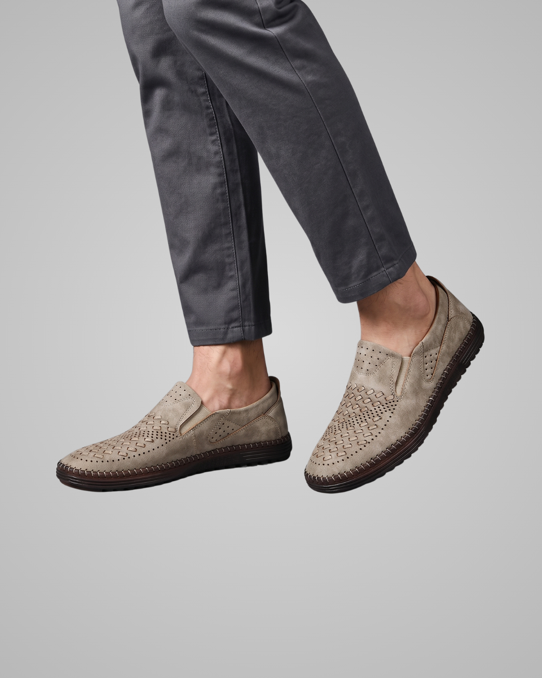 Person wearing brown slip-on shoes with textured sole on a gray background