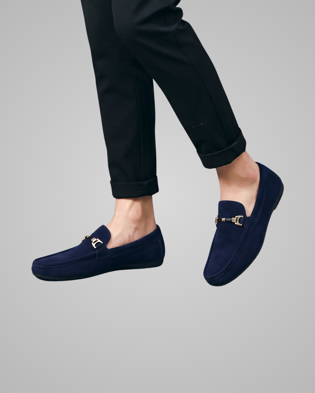 Navy loafers worn with black pants on a gray background