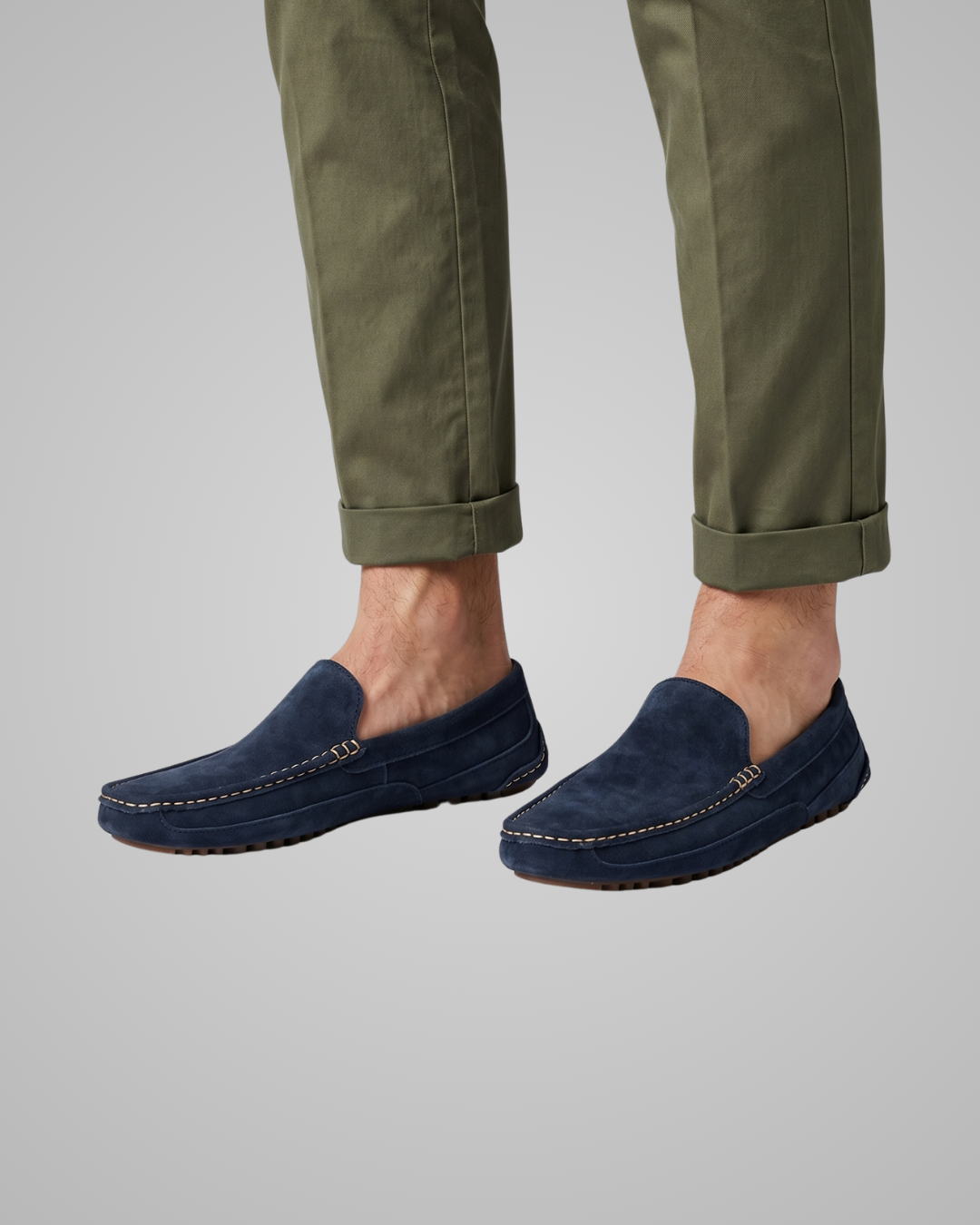 Navy loafers worn with green pants on a light gray background