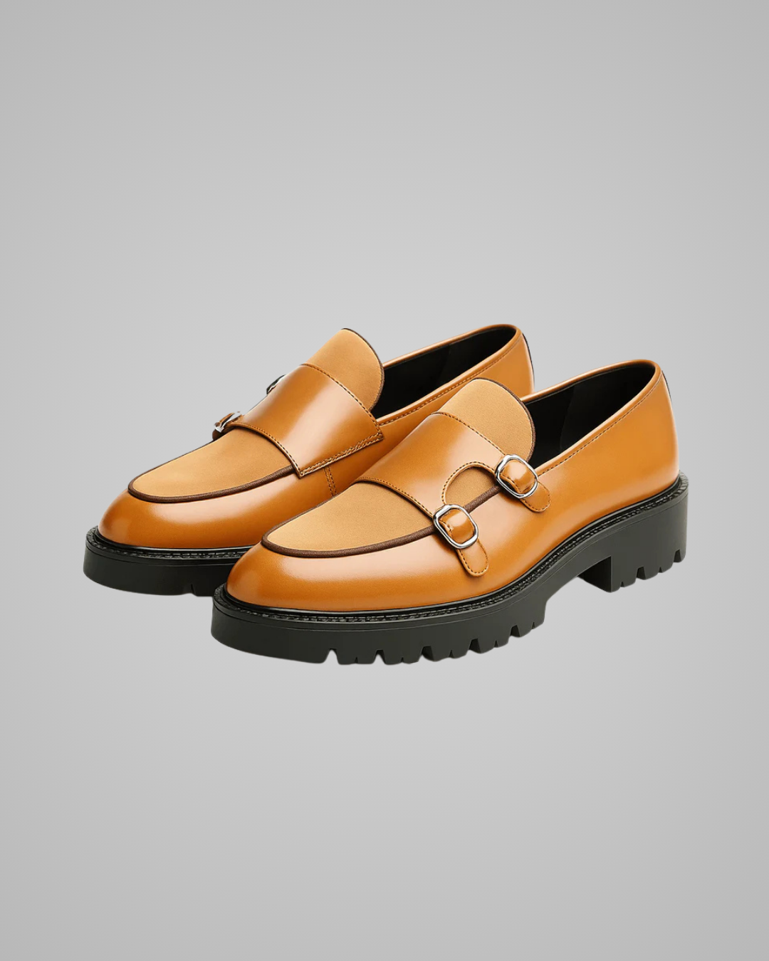 Pair of tan leather shoes with black soles on a gray background