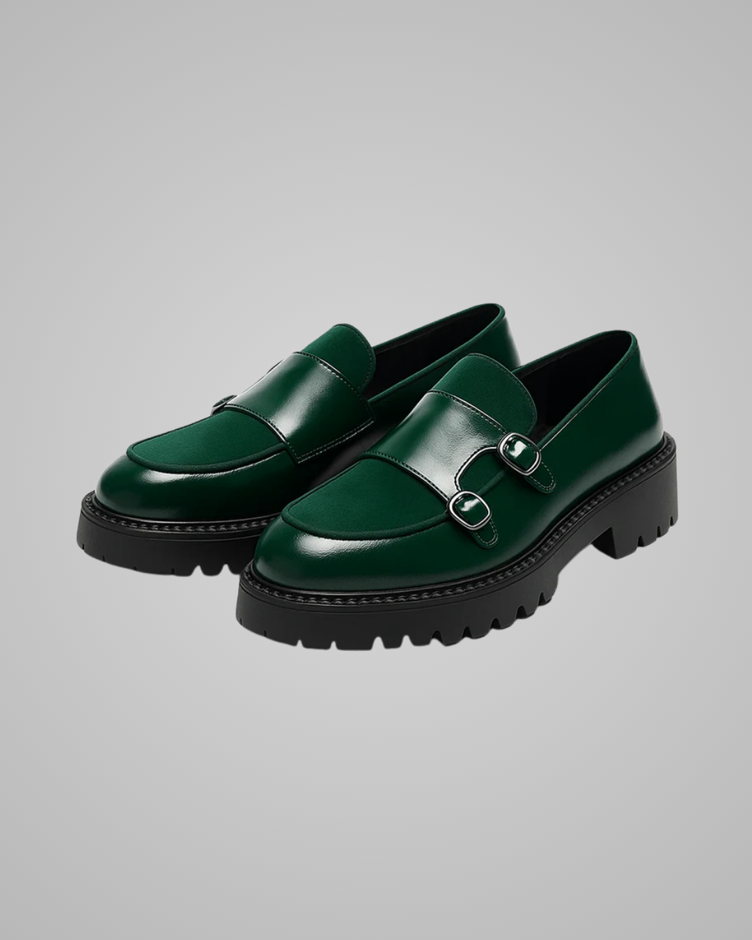 Green leather loafers with black soles on a gray background