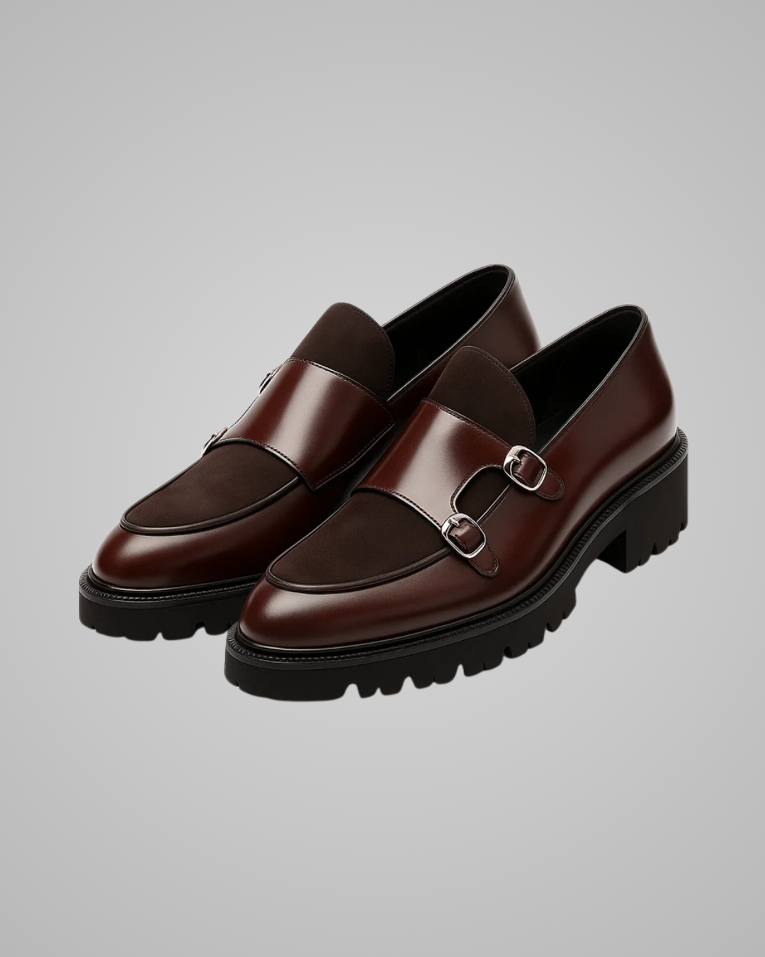 Pair of brown loafers with metal buckles on a gray background