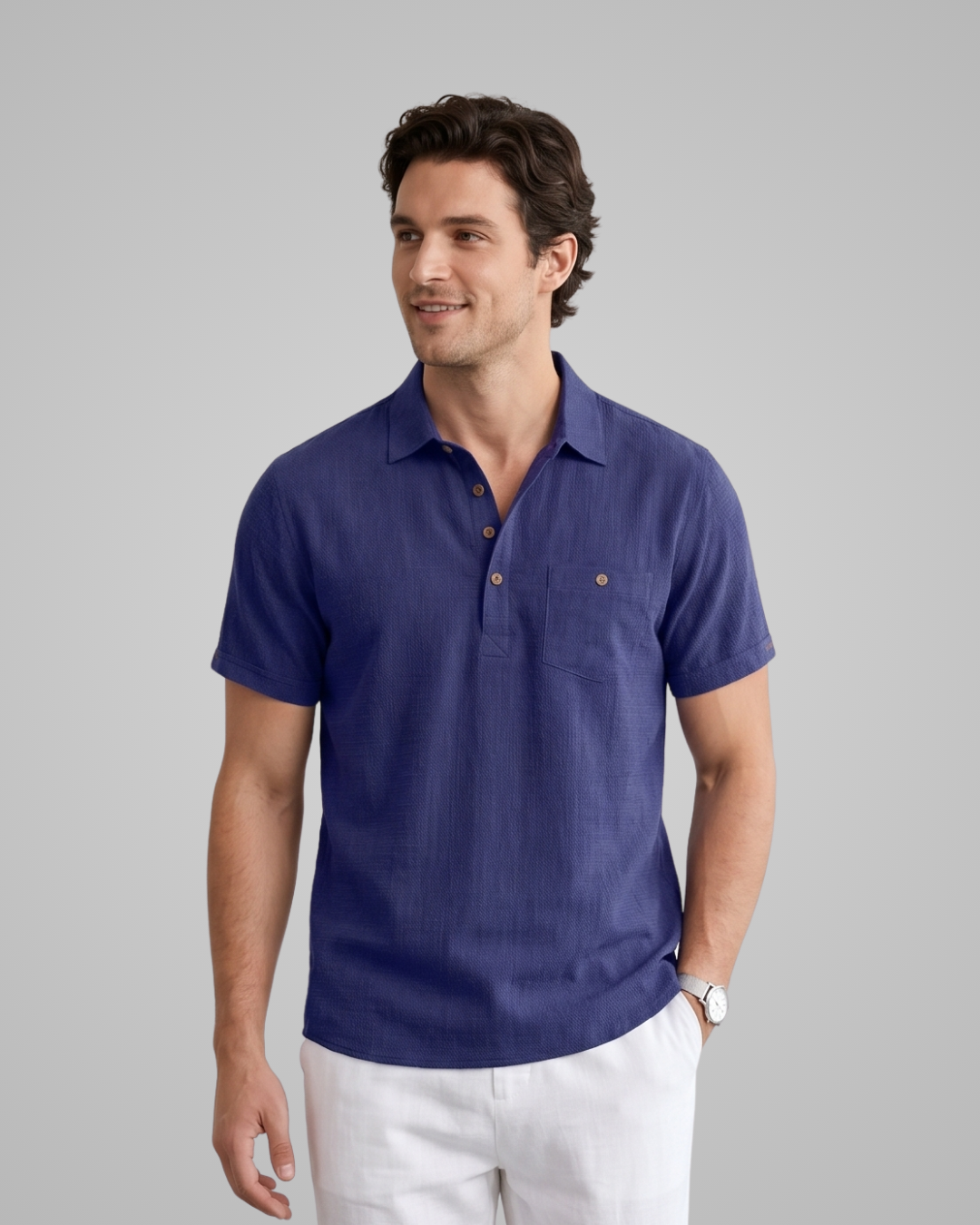 Man wearing a blue polo shirt and white pants on a gray background