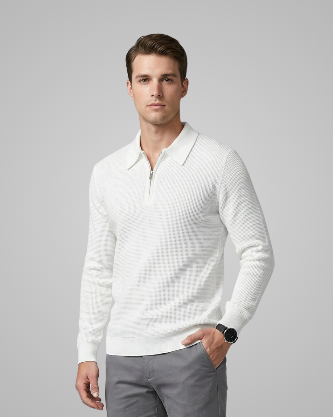 Man wearing a white sweater over a collared shirt on a gray background
