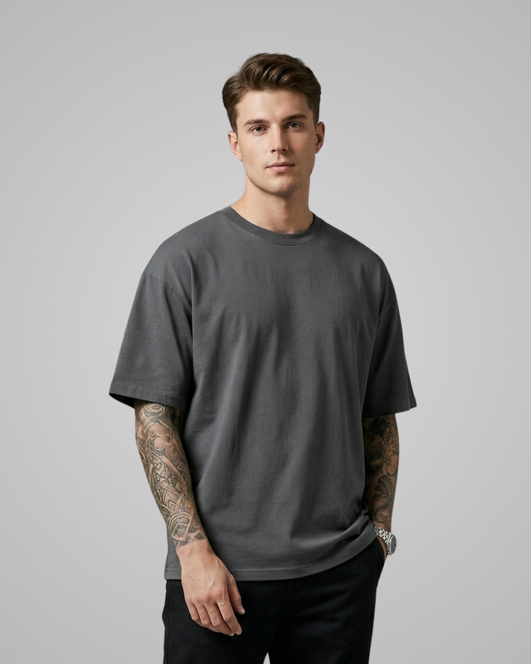 Man wearing a plain dark gray t-shirt against a gray background