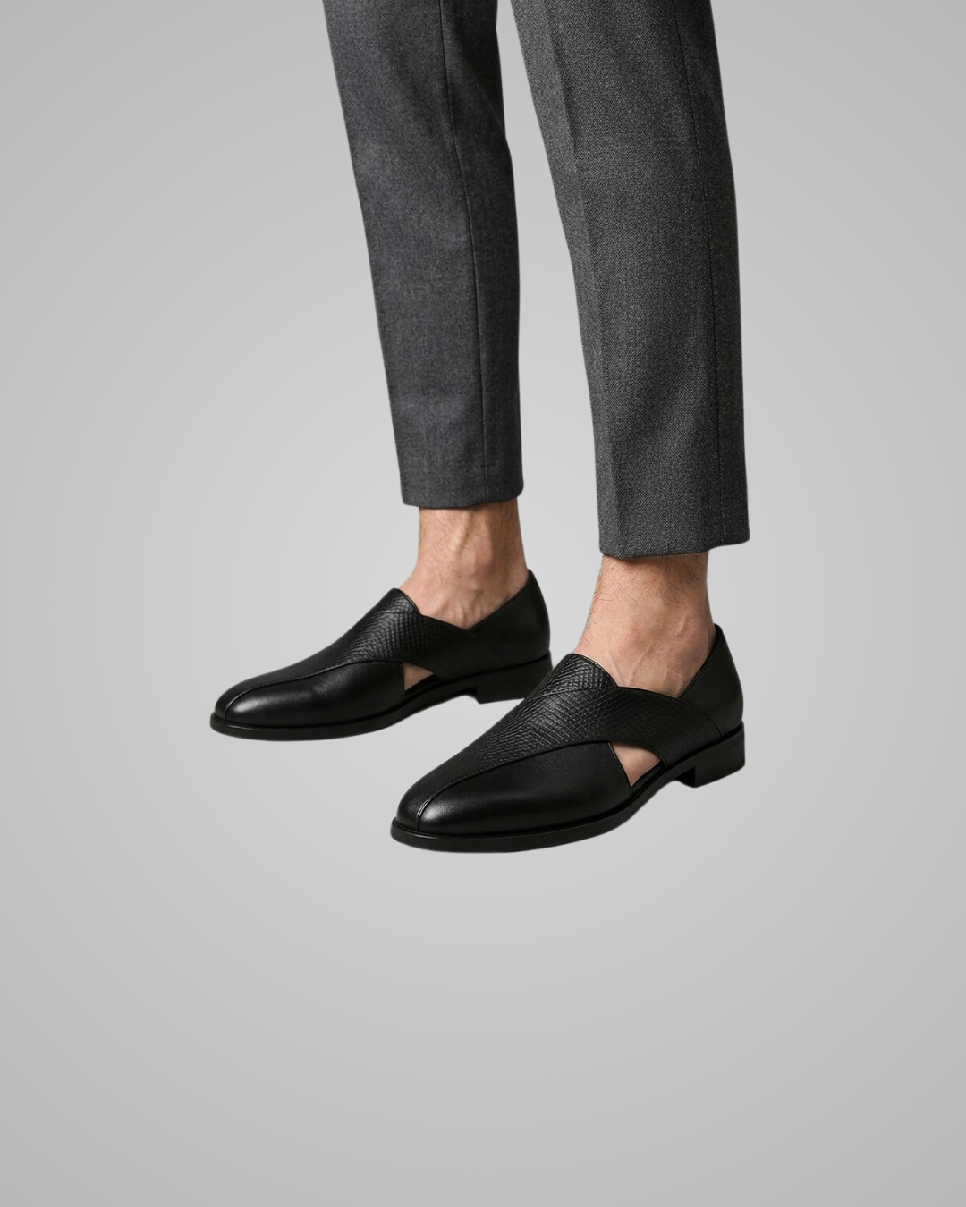 Black dress shoes worn with gray pants on a light gray background