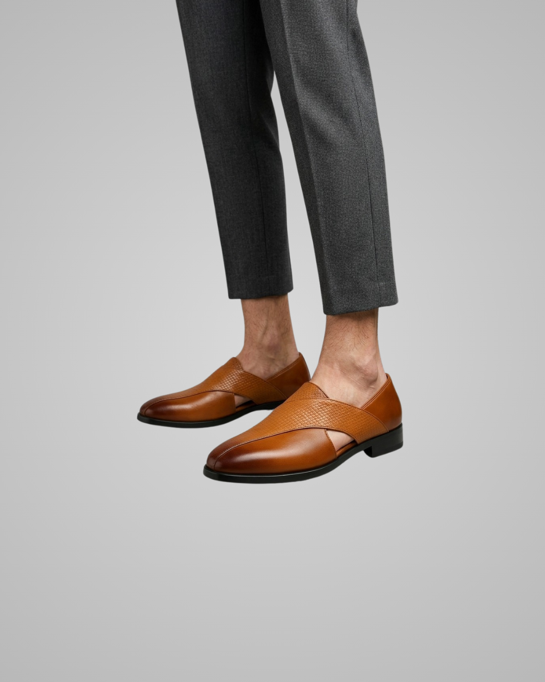 Brown leather shoes worn with gray pants on a light gray background