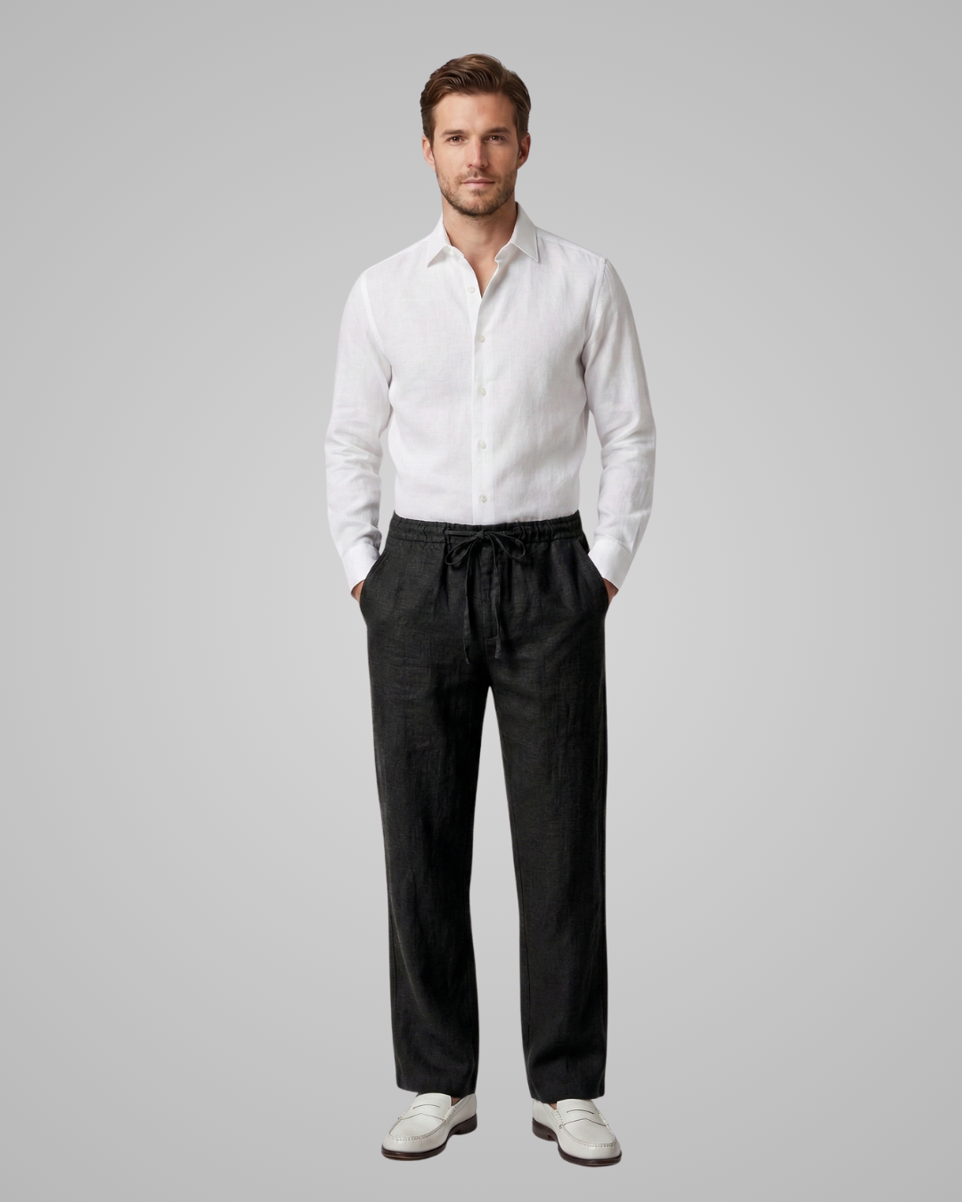 Man wearing a white shirt and black pants on a gray background