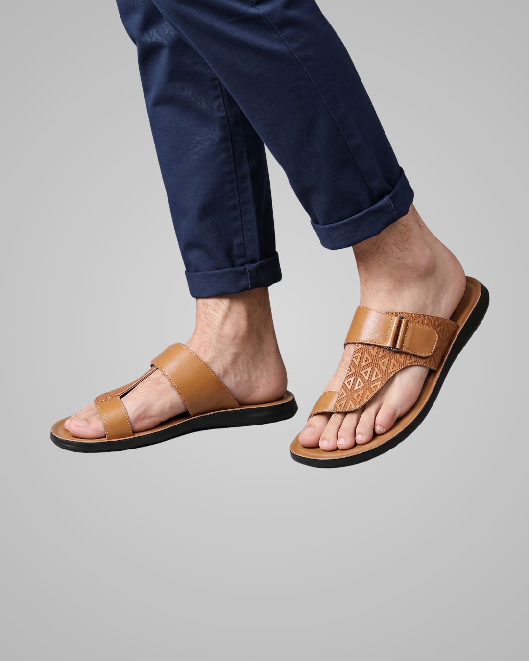 Brown sandals worn with navy pants on a gray background