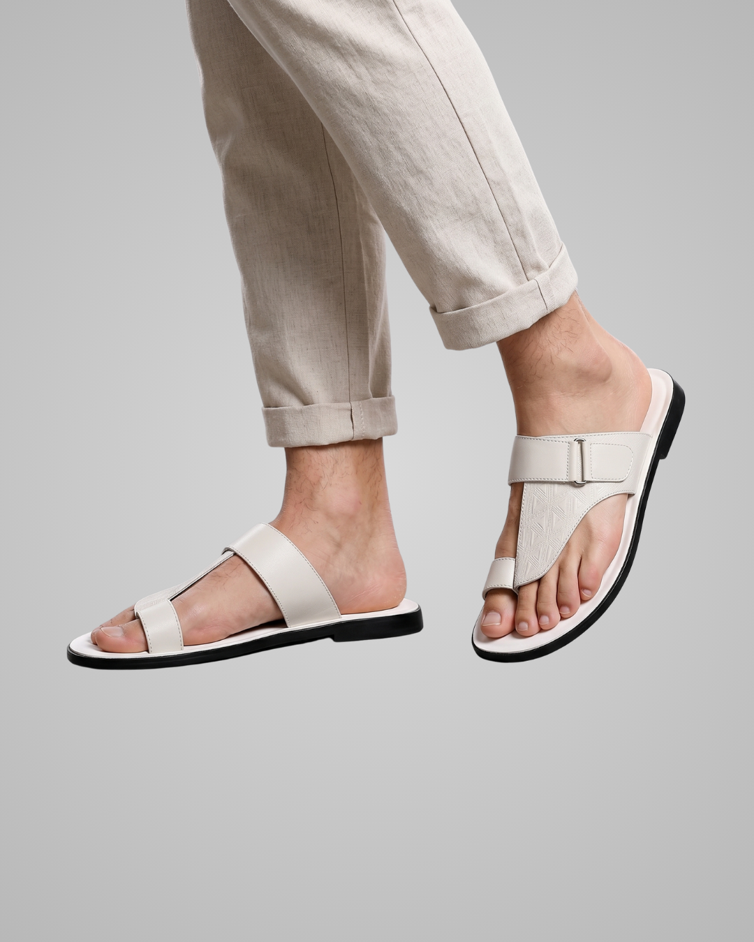 White sandals worn with beige pants on a gray background