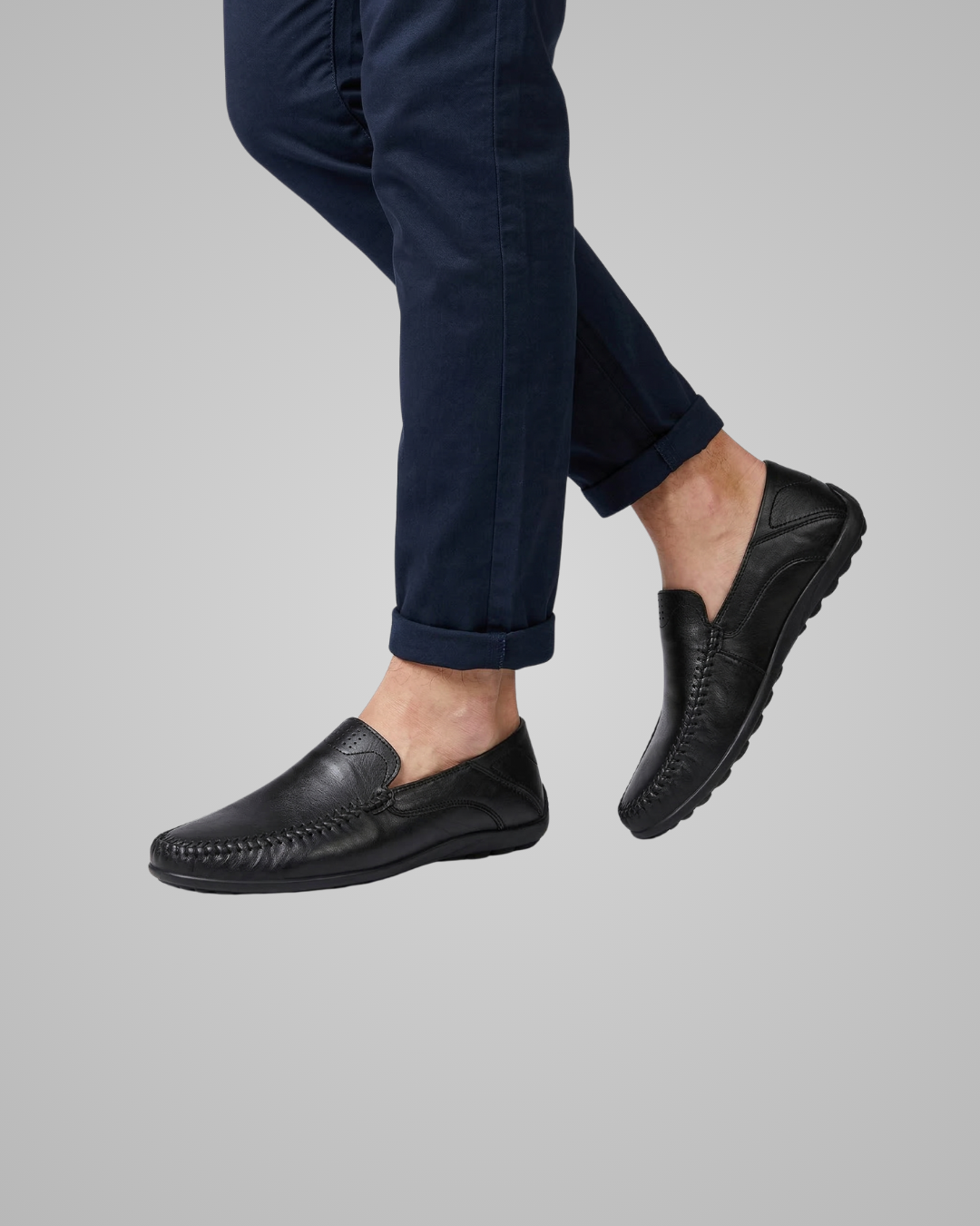 Person wearing black loafers and navy pants on a gray background