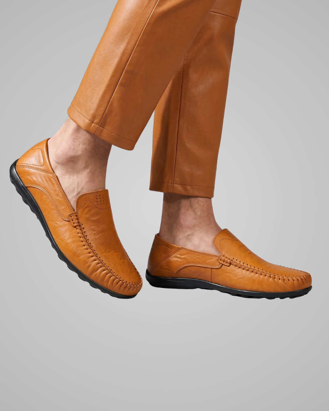 Brown leather loafers worn with brown pants on a gray background