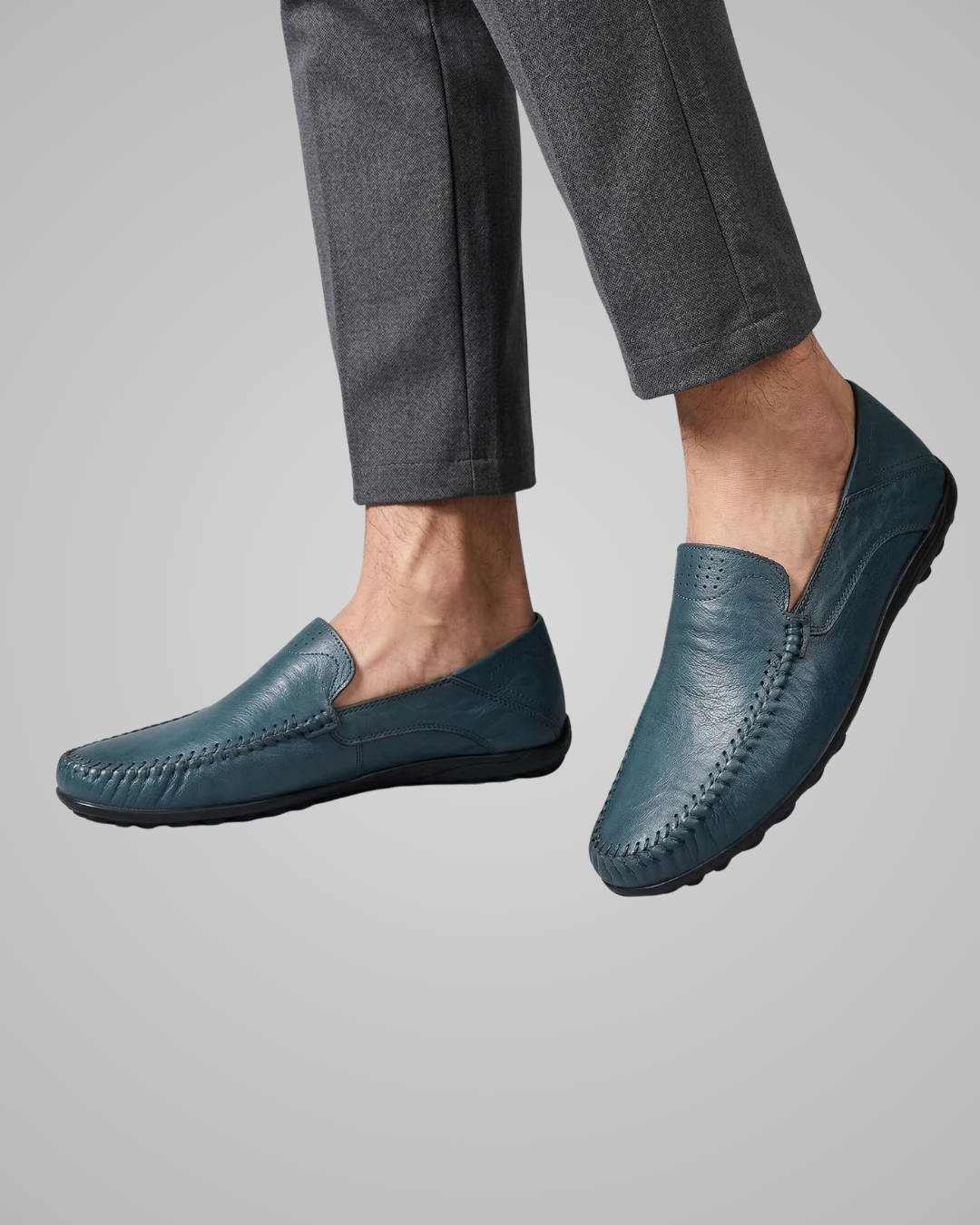Blue loafers worn with gray pants on a light gray background