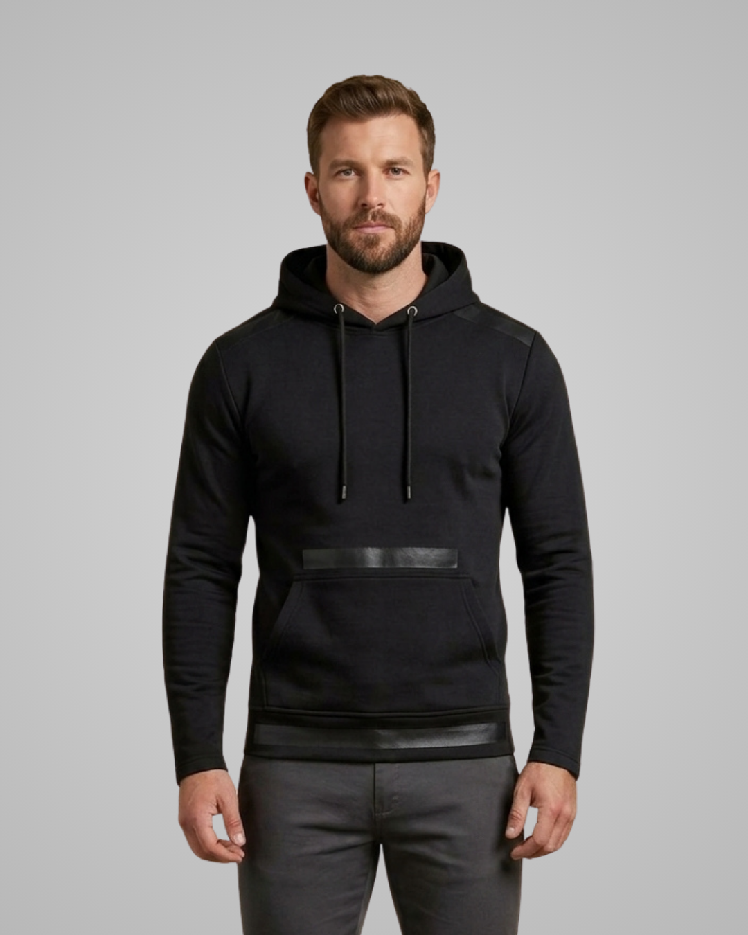 Man wearing a black hoodie with leather accents on a gray background