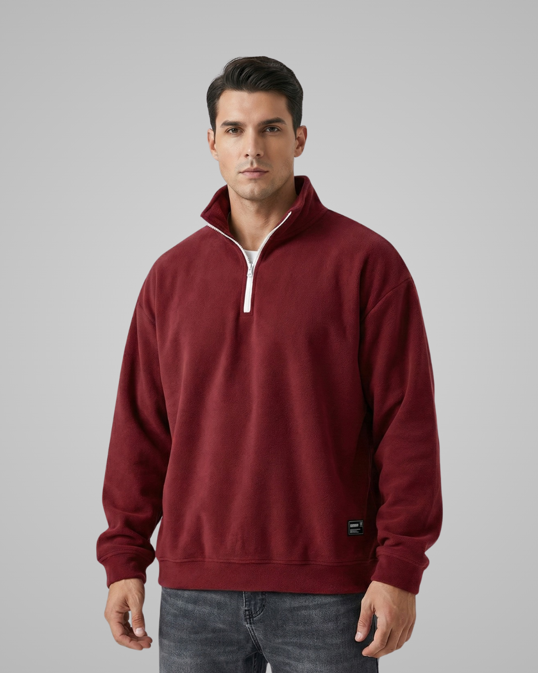 Man wearing a maroon pullover with a white zipper on a gray background