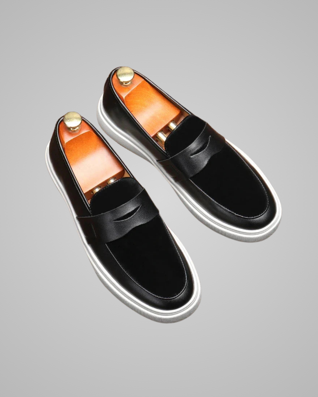 Pair of black loafers with orange insoles on a gray background