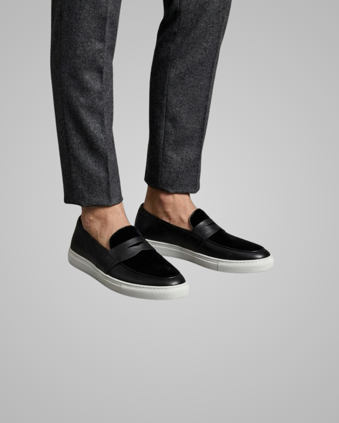 Black loafers worn with gray pants on a light gray background