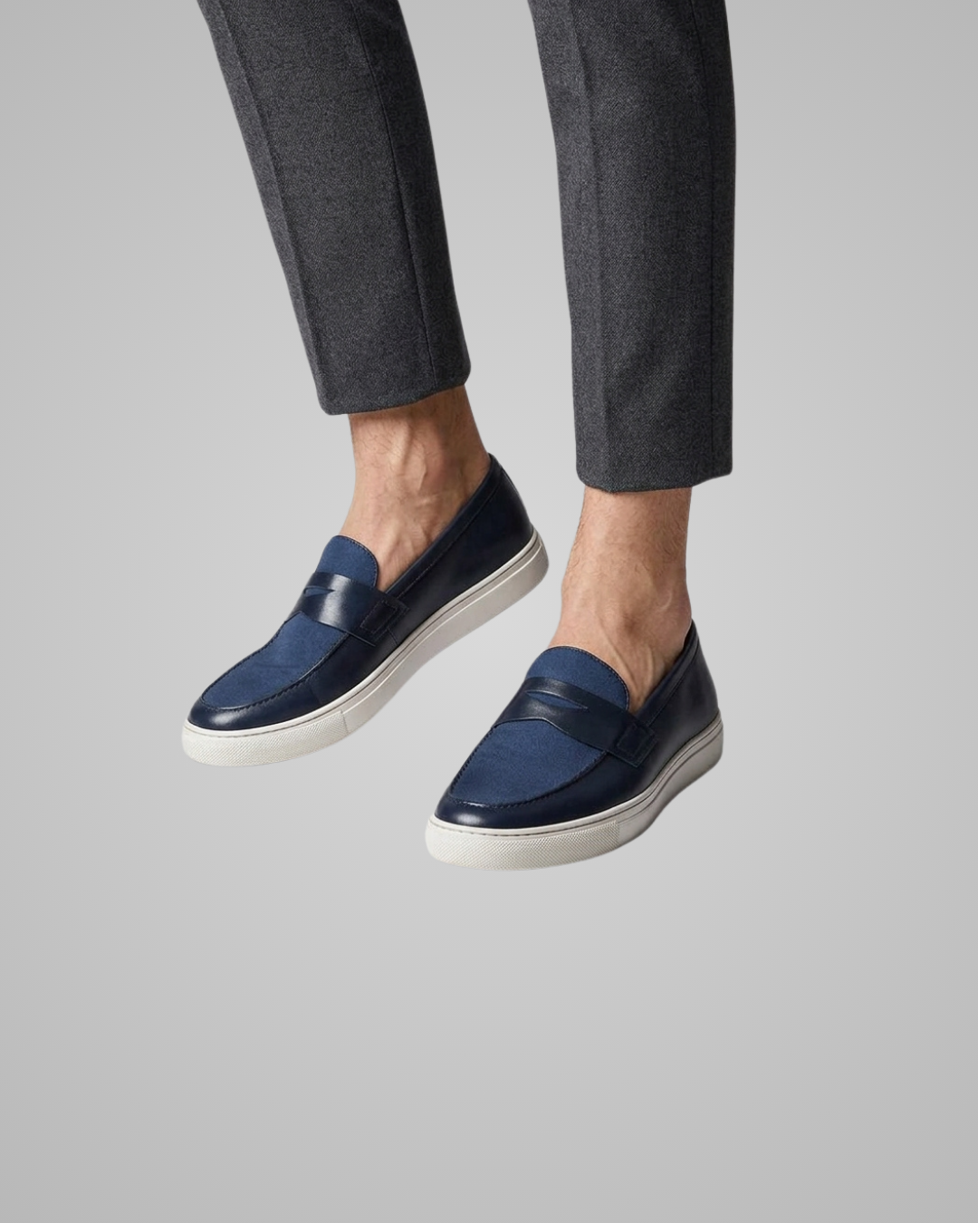 Navy loafers worn with gray pants on a light gray background