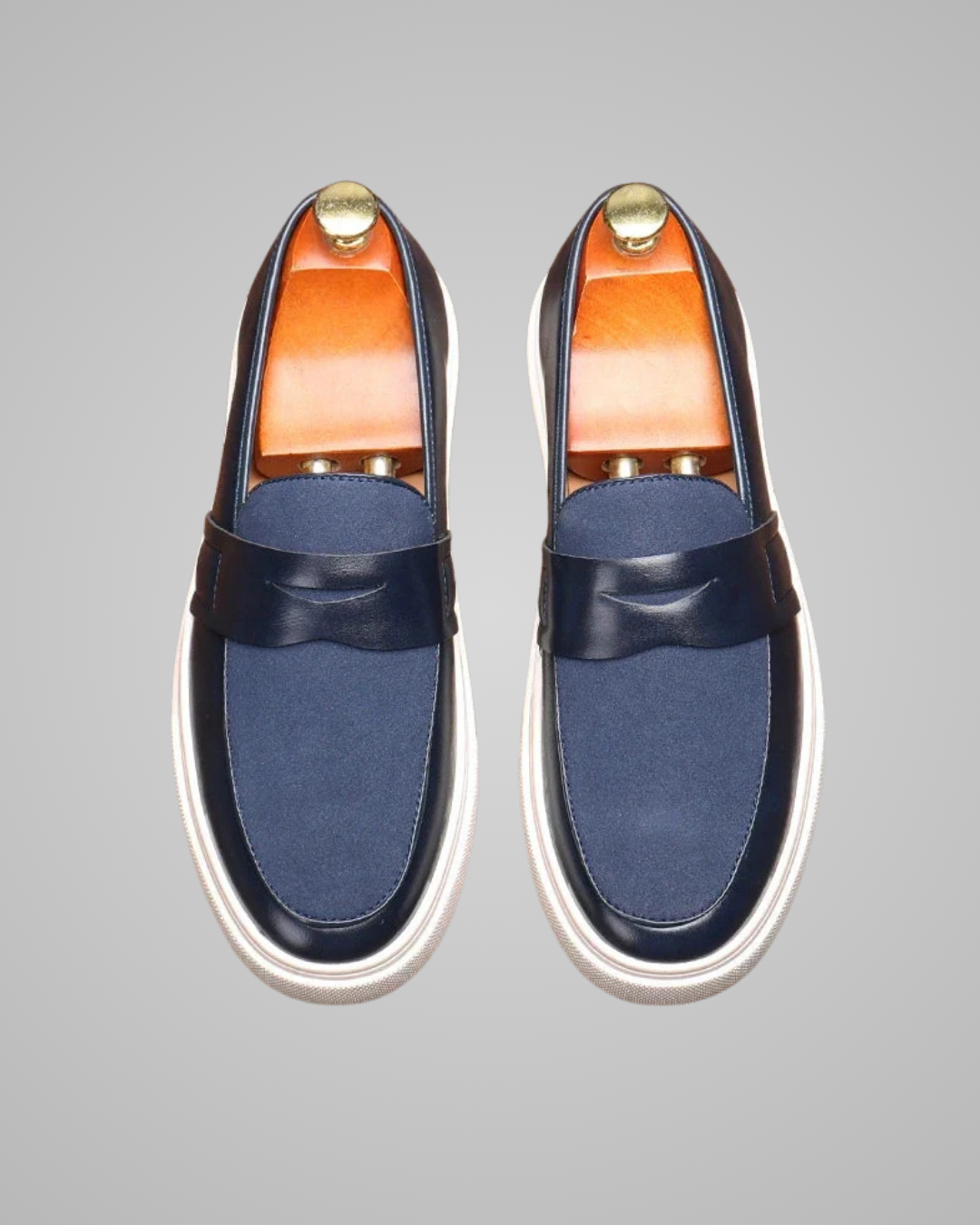 Pair of navy loafers with white soles on a gray background