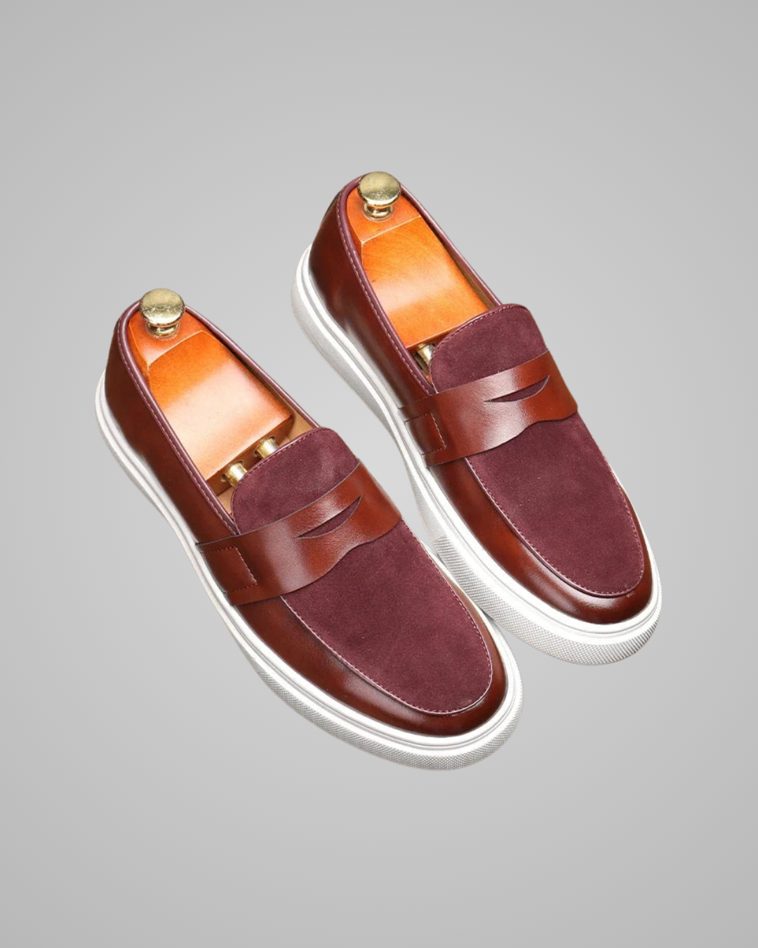 Pair of brown loafers with white soles on a gray background