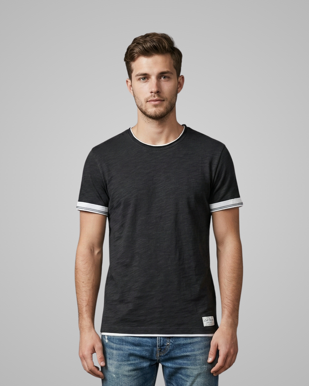 Man wearing a black t-shirt with white trim on a gray background