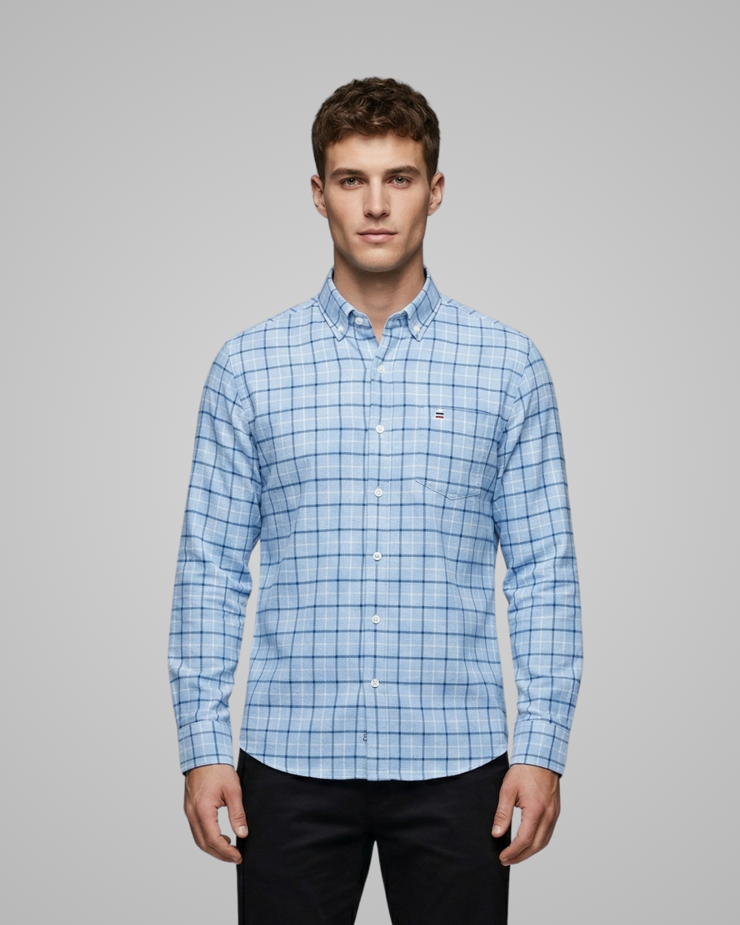 Man wearing a blue checkered shirt against a gray background