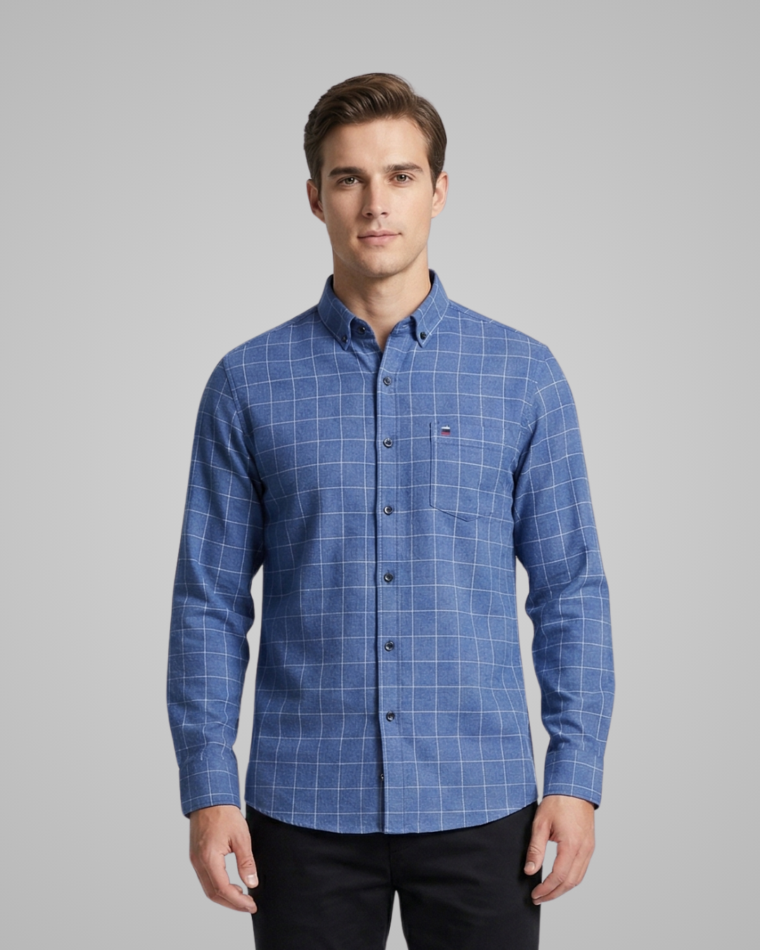 Man wearing a blue checkered shirt against a gray background