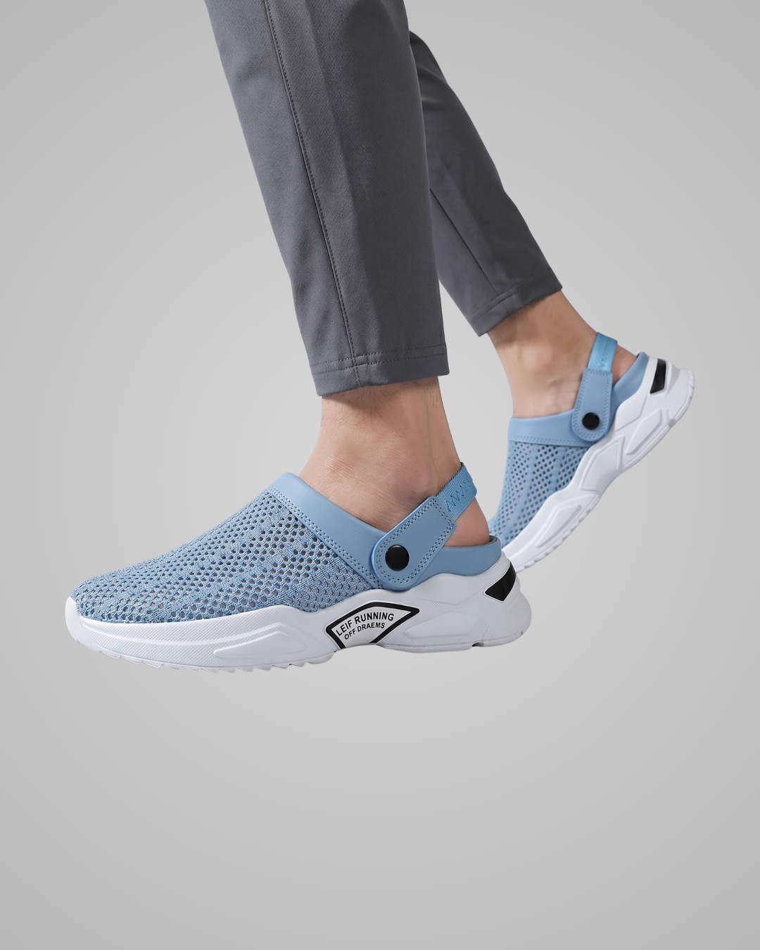 Light blue clogs with white soles worn by a person on a gray background