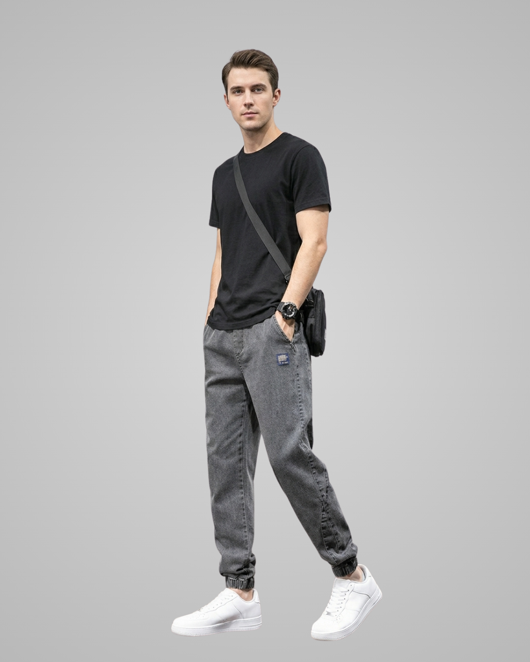 Man wearing a black t-shirt, gray jogger pants, and white sneakers on a gray background
