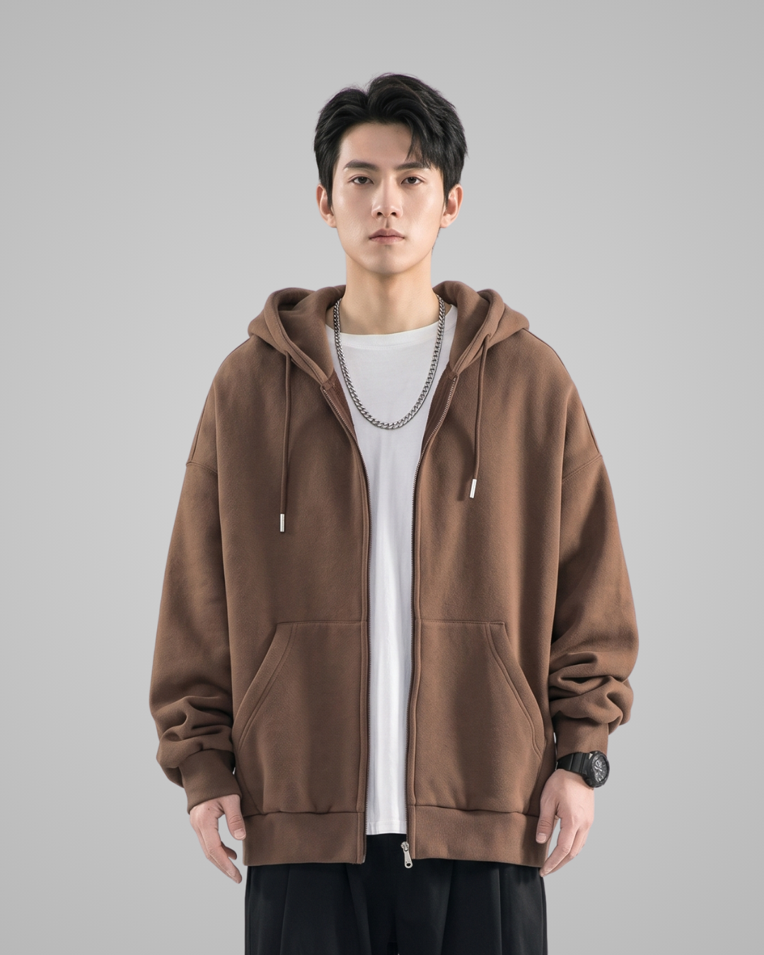 Man wearing a brown hoodie over a white shirt on a gray background