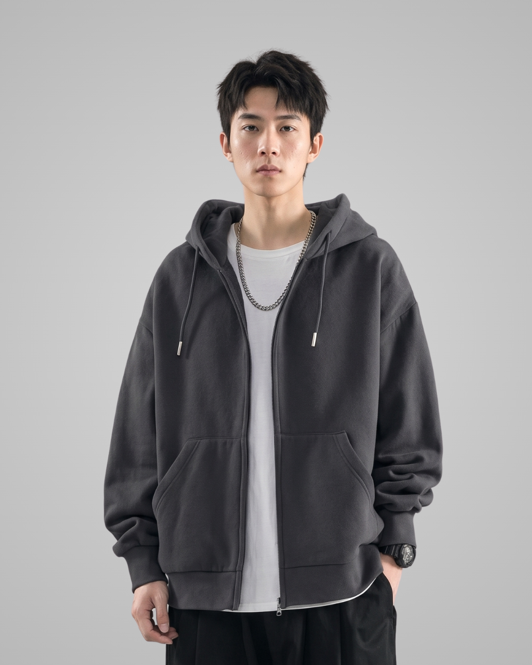 Person wearing a dark gray hoodie over a light gray shirt on a gray background