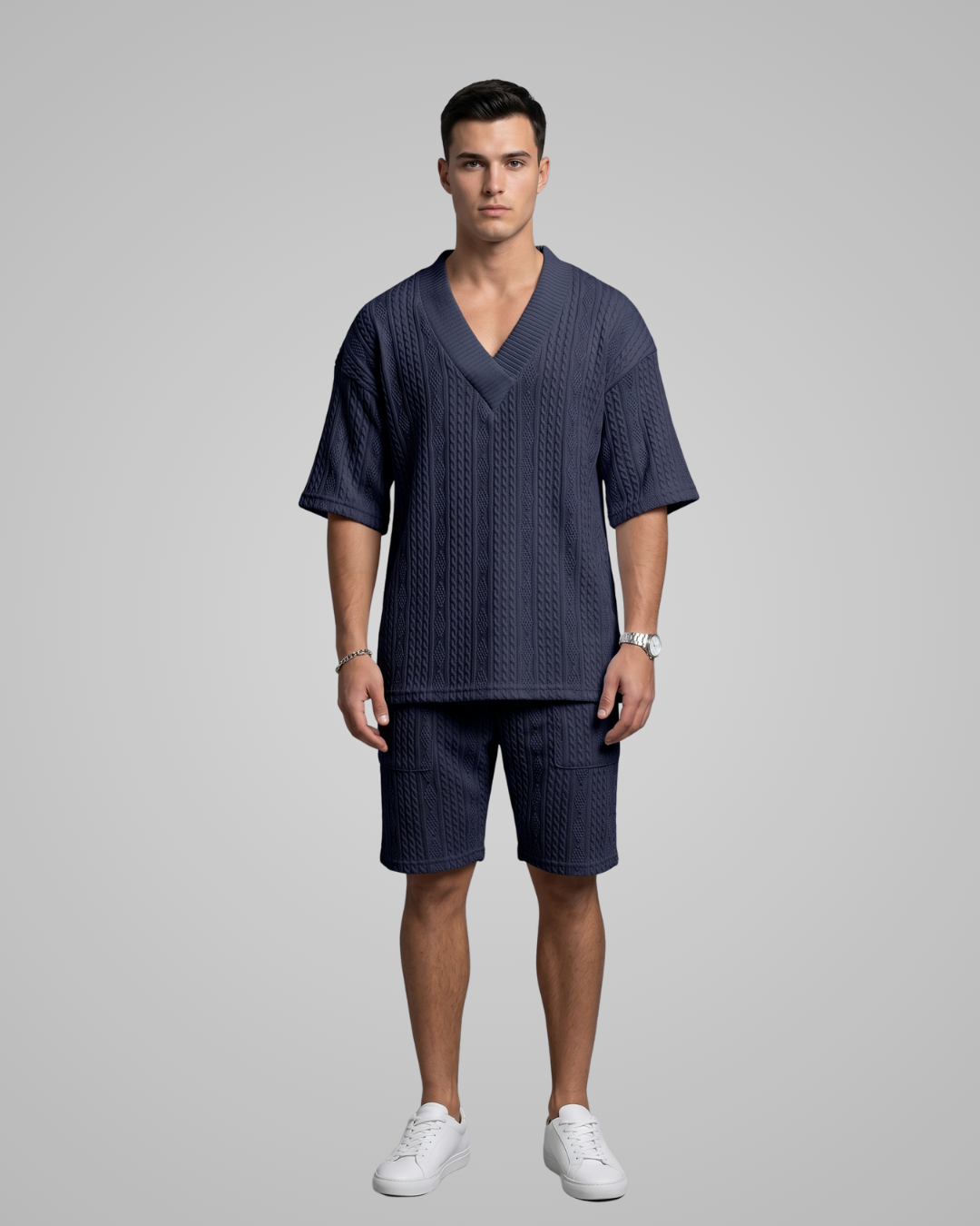 Man wearing a navy blue scrub set with white sneakers on a gray background