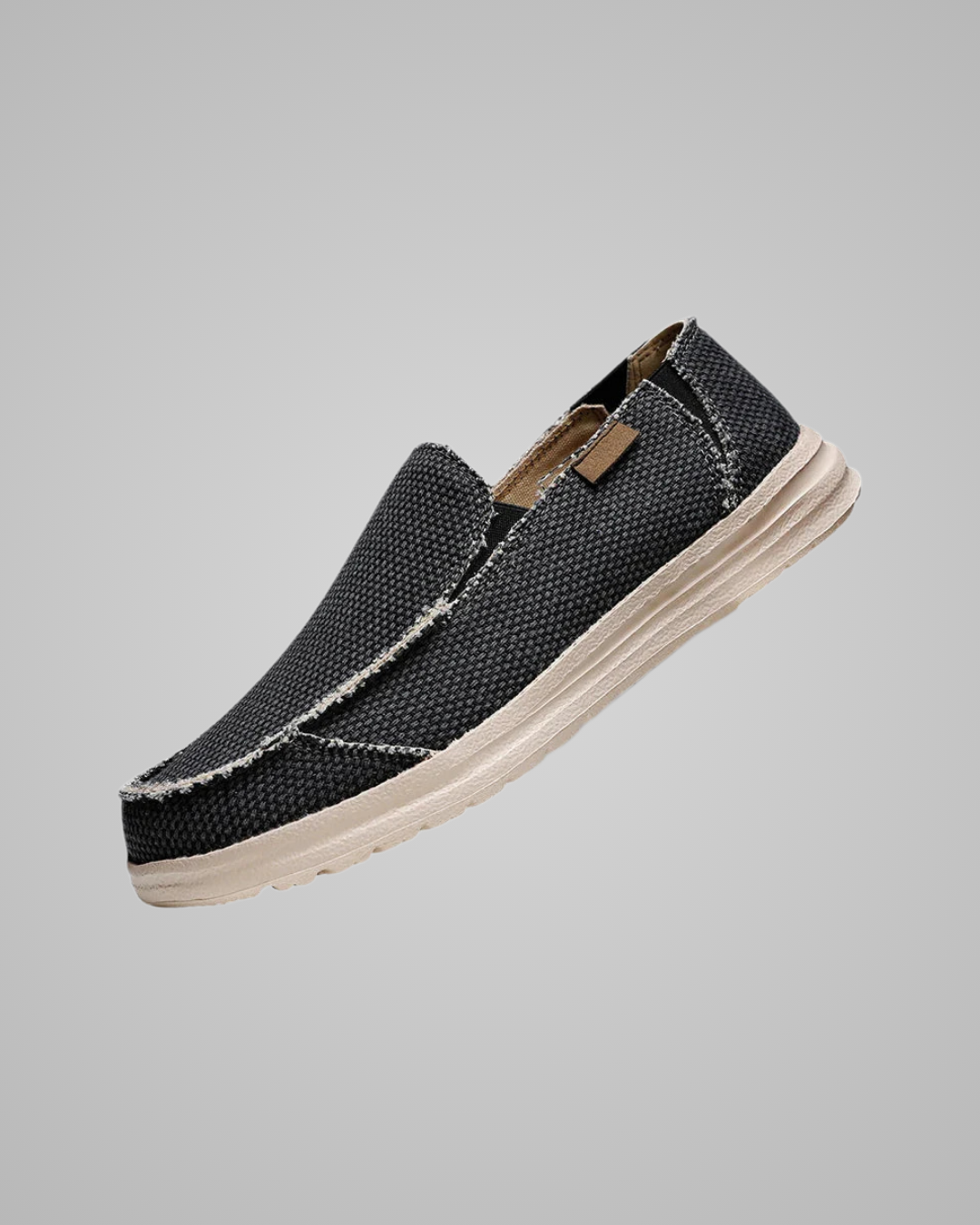 Black slip-on shoe with white sole on a gray background