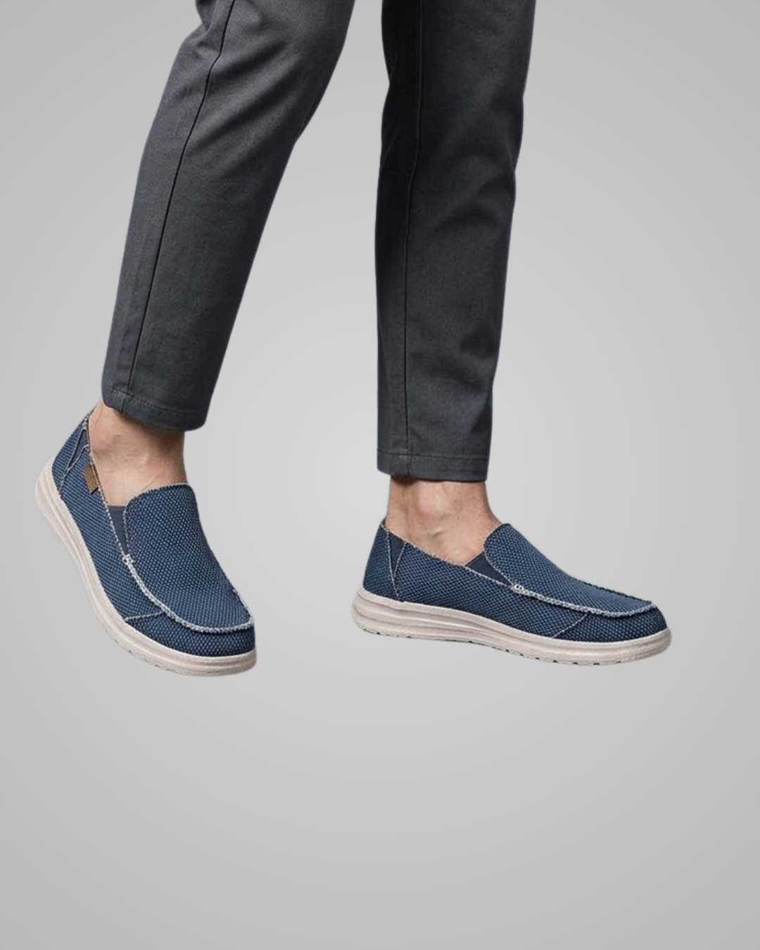Blue loafers worn with dark pants on a gray background