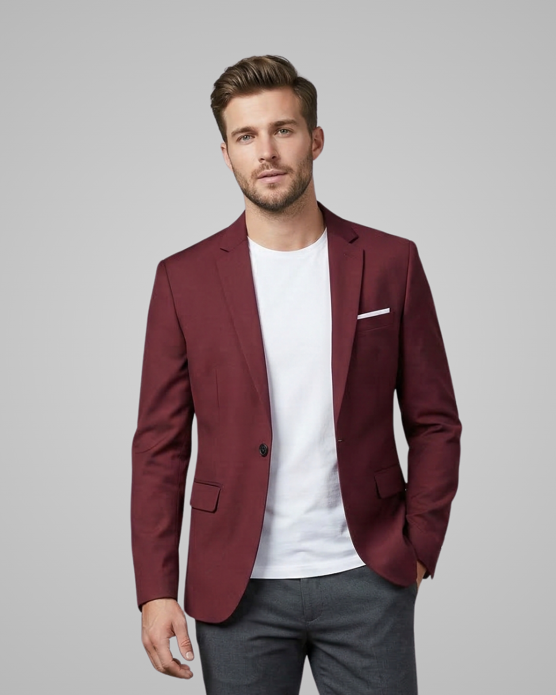 Man wearing a burgundy blazer over a white shirt with gray pants on a light gray background